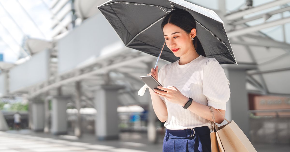 日傘を手に、スマホを見る女性