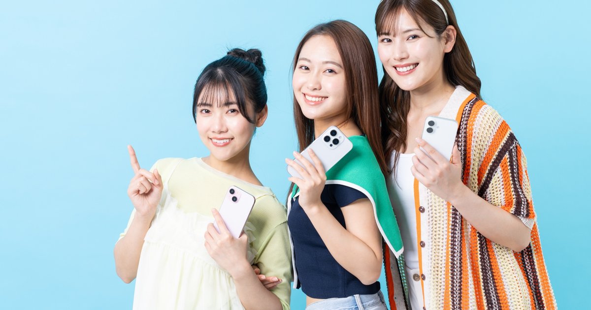 スマホを手に横に並んで笑う3人の女性