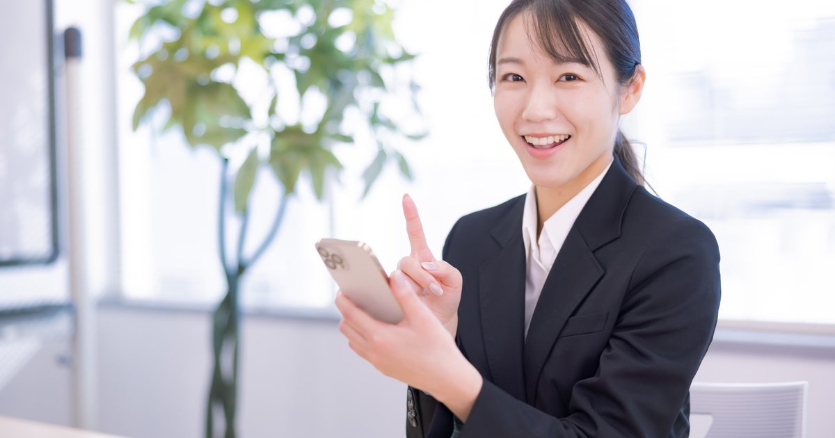 スマホを手に笑顔で案内する女性