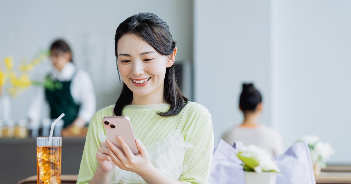 カフェの席でスマホの画面を見る女性